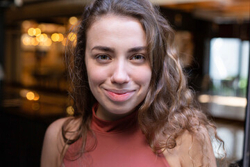 Portrait of european young girl with dark and curly hair with lights behind