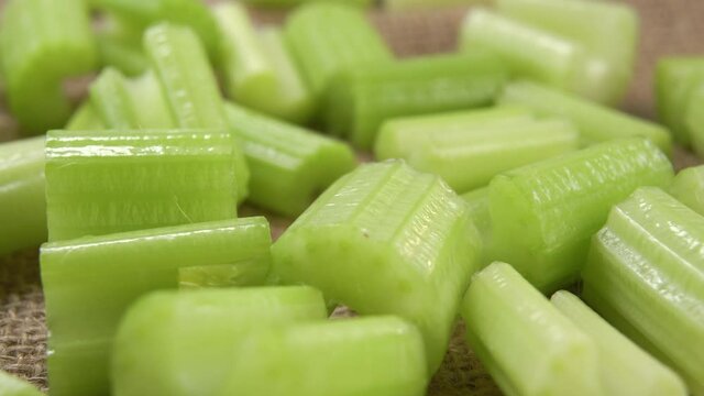 Slices chopped fresh celery stalk on a burlap rough tablecloth. Macro. Dolly shot. Rustic view