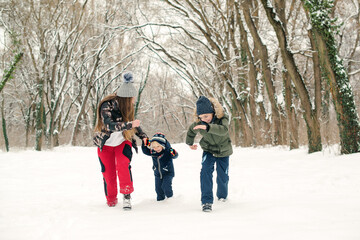 Mother with children having fun on a walk in winter park. Snowy winter weather. Happy christmas holidays.