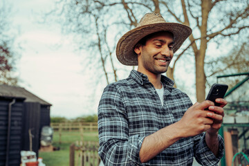 Mixed race male farmer texting on cellular device while working outdoors
