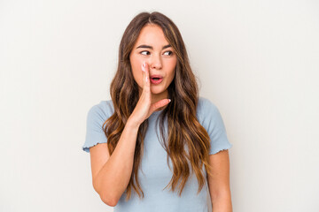 Young caucasian woman isolated on white background is saying a secret hot braking news and looking aside