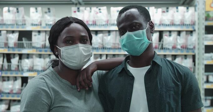 Front of woman lean on boyfriend discuss goods in supermarket. African couple in facial mask buy goods check with each other's ideas. quarantine,self-isolation,close relationship,coronavirus pandemic