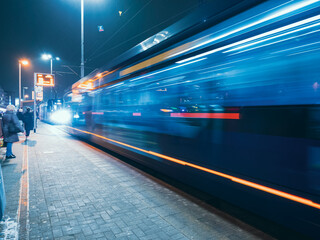 Fototapeta na wymiar the tram leaves the stop in night city, motion blur view