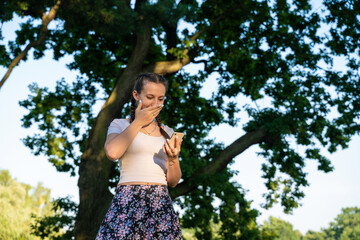 Girl phone. Euphoric screaming young girl holding smartphone showing winner gesture at sunny day in...