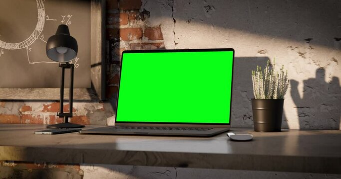 Laptop with the blank green screen on the office table. Loft style. Camera rotation with a little zoom. UHD 4k. Contain screen mask for tracking display