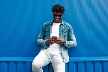 african man typing sms on blue background, 5g internet concept, high speed internet on phone