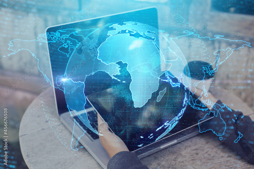 Poster Close up of hands at desktop using laptop and tablet with creative glowing globe interface on dark background. Technology, network and online data concept. Double exposure.