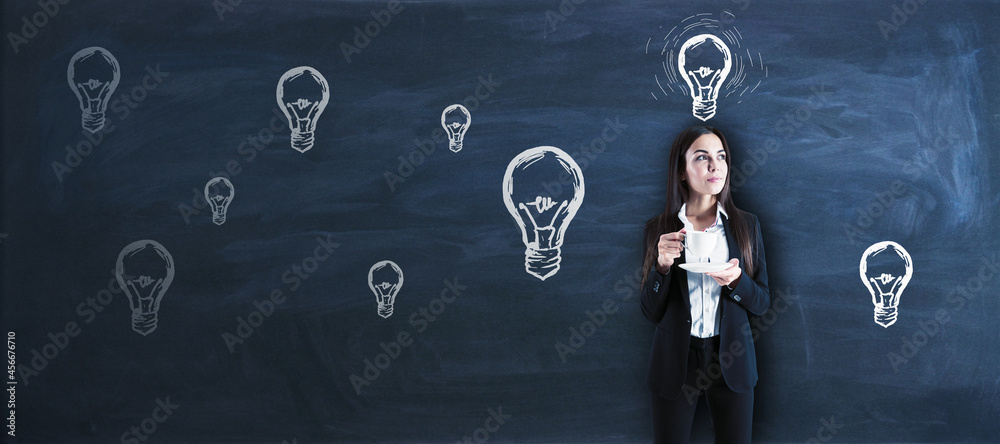 Wall mural attractive young european businesswoman with coffee cup standing on chalkboard wall background lamp 