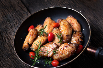 Baked chicken wings served with different sauces in a pan. Black background
