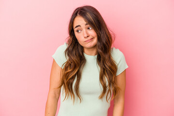 Young caucasian woman isolated on pink background shrugs shoulders and open eyes confused.