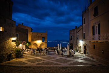 the little square of borgio verezzi full of people in its restaurants during a warm summer evening...