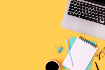 Homeschooling workspace with laptop, coffee and stationery on a yellow background. E-learning, online study concept with copy space.