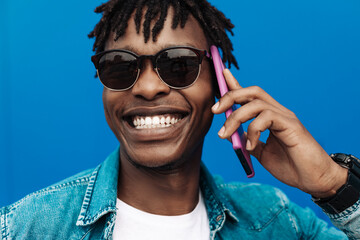 african man calling on the phone on blue background, 5g internet concept, high speed internet on phone