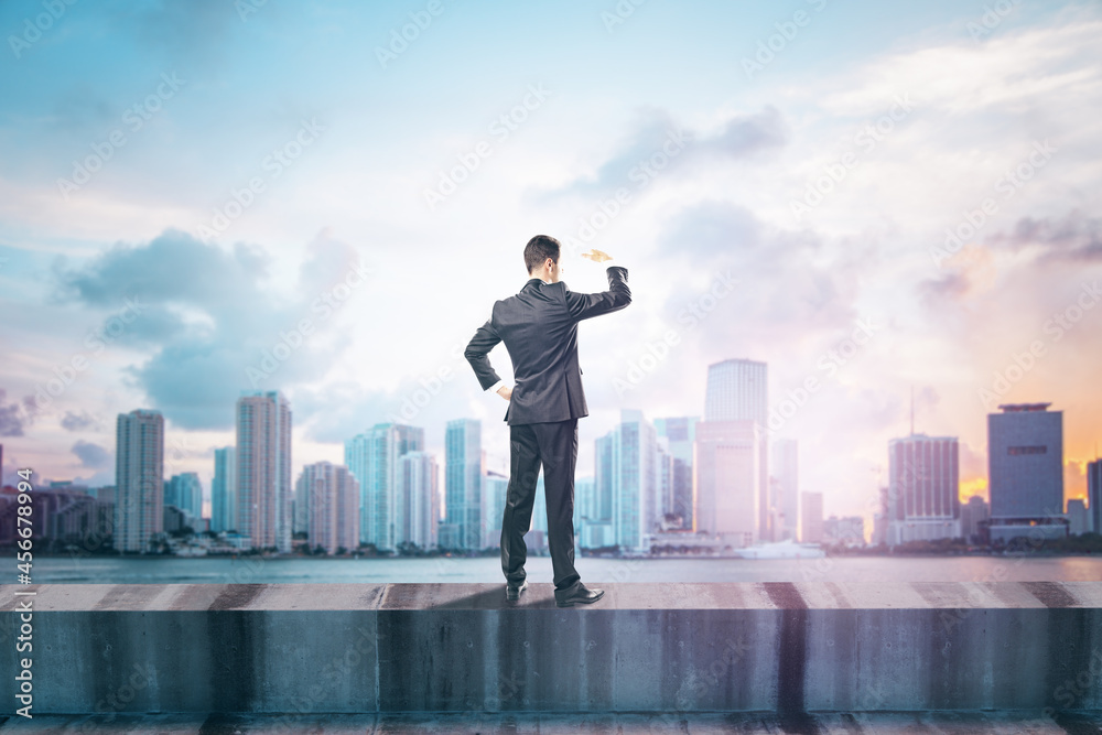Aufkleber back view of young man standing on concrete edge of building on city background with mock up place i