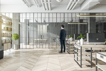 Businessperson standing in modern coworking office interior with bright city view and wooden flooring. Design and workplace style concept.