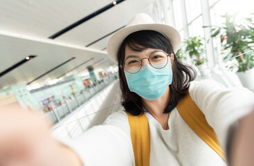 Fototapeta na wymiar Asian Young Female tourist wearing protective face mask taking selfie.