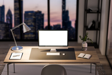 Close up of empty white computer monitor in creative modern nighttime office studio interior with glass partition and window with city view, wooden flooring. Workplace and architecture concept. 