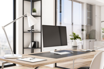 Close up of empty computer monitor in creative modern daylight office studio interior with glass partition and window with city view, wooden flooring. 