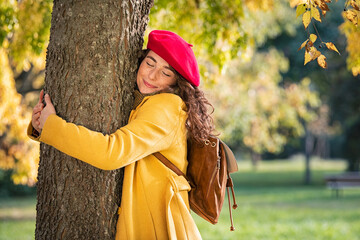 Young woman hugging tree in atumn at park