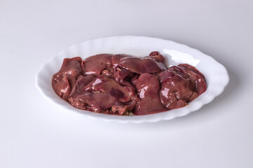 Raw chicken liver meat in a plate on a light background
