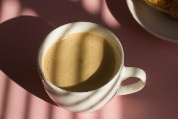 Cup of coffee with foam on a pastel background with shadows