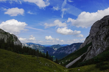 Obraz premium view to a deep valley with mountains and white clouds on the blue sky