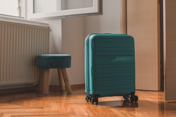 Travel suitcase behind the open door of hotel apartment room