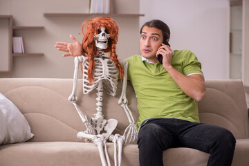 Young man sitting on the sofa with female skeleton
