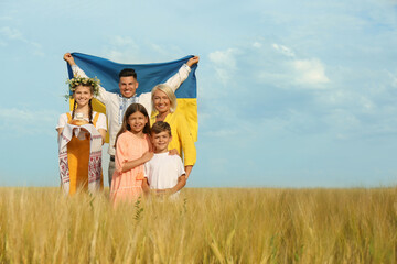 Happy family with national flag of Ukraine and treat in field. Space for text