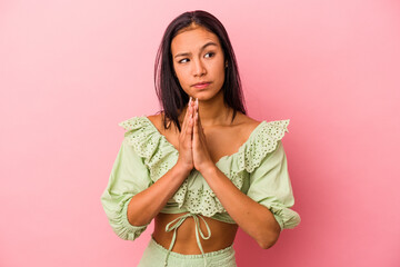 Young latin woman isolated on pink background  praying, showing devotion, religious person looking...
