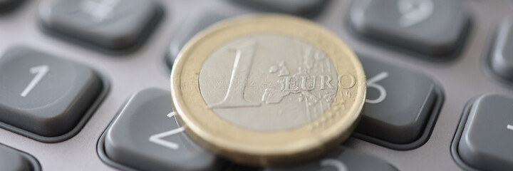 One euro coin is on calculator closeup