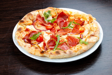 Pizza with Parma ham and cherry tomatoes. On a wooden background