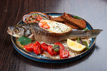Seabass with spinach and cream sauce. On a wooden background