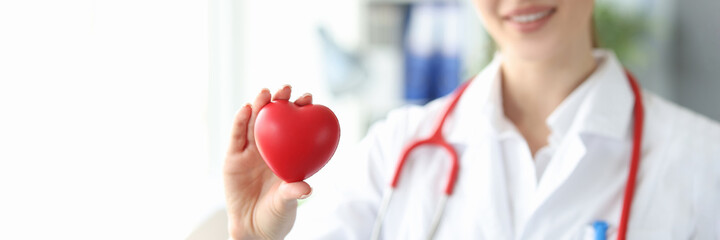 Woman cardiologist holds small red heart in her hand