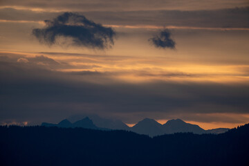 Naklejka premium Golden sunrise on the mountains at a september morning with orange cloudy sky and view of the alps in austria