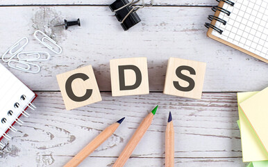 CDS text on wooden block with office tools on wooden background