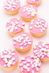 Colorful cupcakes on a pink background.