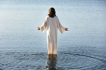 Jesus Christ in water lit by morning sun, back view