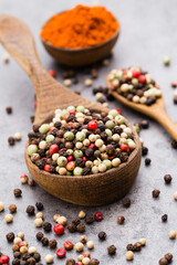 Peppercorn mix in a wooden bowl on grey table.