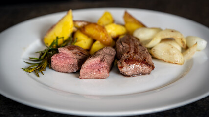 the roasted tenderloin from the red deer calf with fries potatoes and roasted onions is a delicious meal