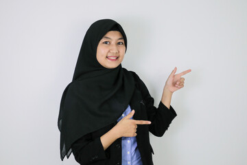 Happy Young Asian Islam woman wearing headscarf is smile and pointing beside.