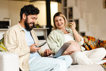 Bearded man and pregnant woman while sitting on couch