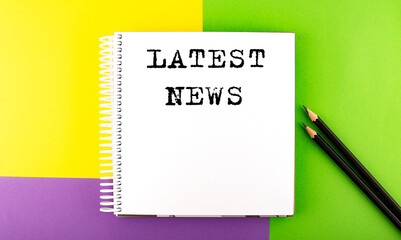 Minimal work space : sketchbook on the colorful background with LATEST NEWS text