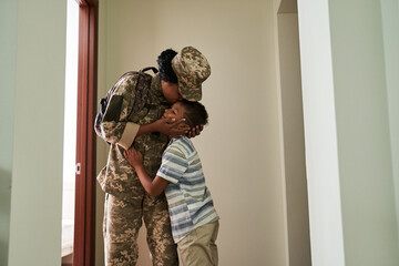 Little boy kissing with his soldier mother while seeing off her to the army
