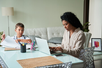 Woman wearing domestic clothes working at the table at her laptop