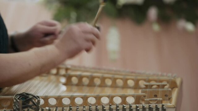 Elderly caucasian woman playing cymbals, close-up. The musician quickly strikes the strings with wooden sticks.