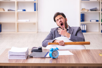 Young male employee in oversleeping concept