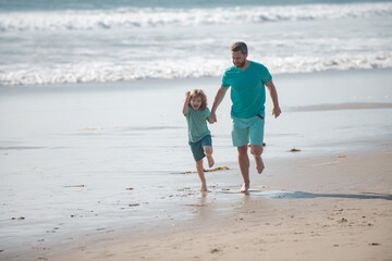 Father and son running on summer beach. Dad and child having fun outdoors.