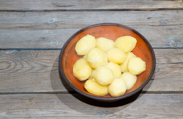 Cooking potatoes on an old wooden table. Raw potatoes in a yellow saucepan on a wooden table. Old wooden boards and vegetables.