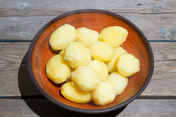 Cooking potatoes on an old wooden table. Raw potatoes in a yellow saucepan on a wooden table. Old wooden boards and vegetables.